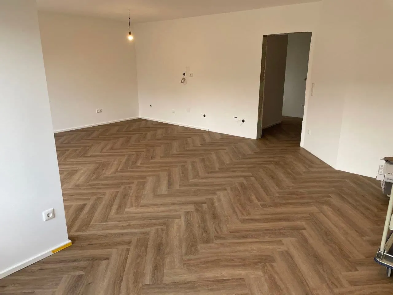 Fertiger Wohnraum mit Vinylboden in Fischgrätoptik, Blick zur offenen Tür