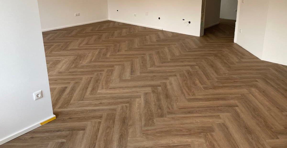 Wohnraum mit fertig verlegtem Vinylboden in Fischgrätoptik in warmer Eichenfarbe